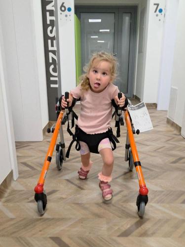 Dziecko ćwiczy samodzielne przemieszczanie się z balkonikiem podczas rehabilitacji NDT-Bobath. 